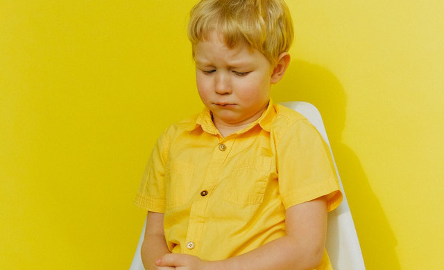 Sad child sitting on a white chair.